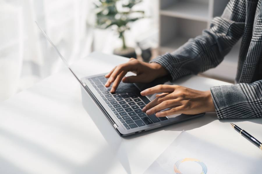 Pessoa digitando em laptop em ambiente de trabalho, simbolizando o uso de IA nas empresas no dia a dia corporativo 